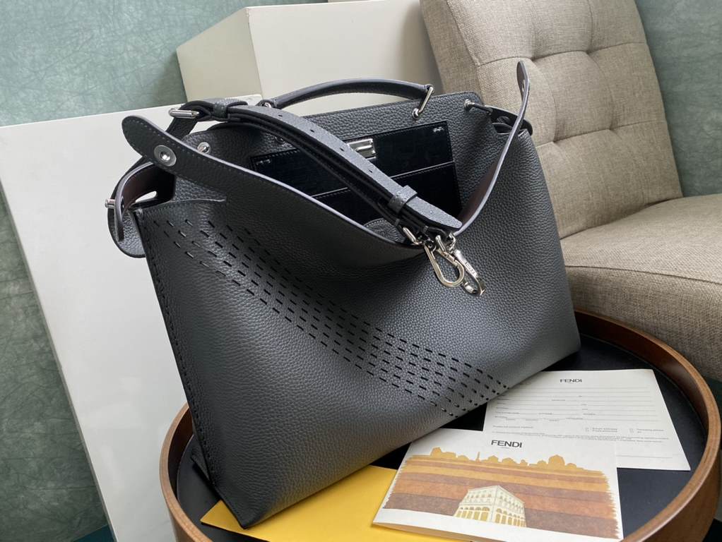 Minimalist design model lightweight handbag with two compartments separated by a rigid panel. Briefcase handles with adjustable, removable shoulder strap. Features interior patch pocket and signature twist lock. In gray 