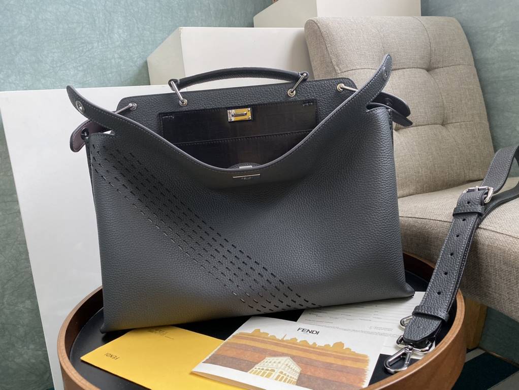 Minimalist design model lightweight handbag with two compartments separated by a rigid panel. Briefcase handles with adjustable, removable shoulder strap. Features interior patch pocket and signature twist lock. In gray 