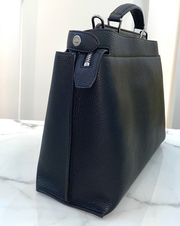 Minimalist design model lightweight handbag with two compartments separated by a rigid panel. Briefcase handles with adjustable, removable shoulder strap. Features interior patch pocket and signature twist lock. In black