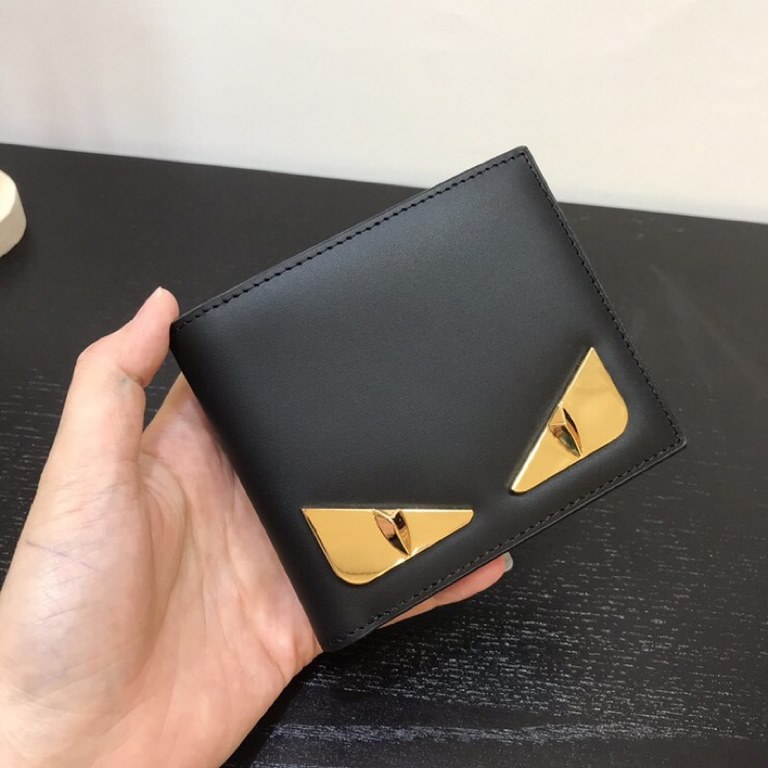 FEND1  Bifold wallet with inside   eight credit card holders and two bill compartments. Made of black calf leather, BAG BUGS eye graphic decorated with gold plated finish metal appliqué, size 11.510.