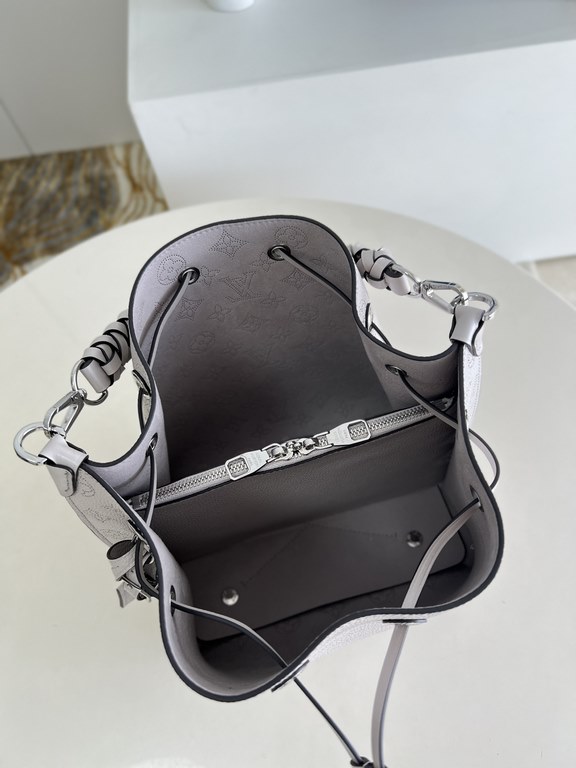 ExclusiveExclusive to M58788 in pearlized grey, this Muria bucket bag is crafted from cutout cowhide leather that lends a metallic sheen to the perforated Monogram pattern, and is finished with a leather name tag and key