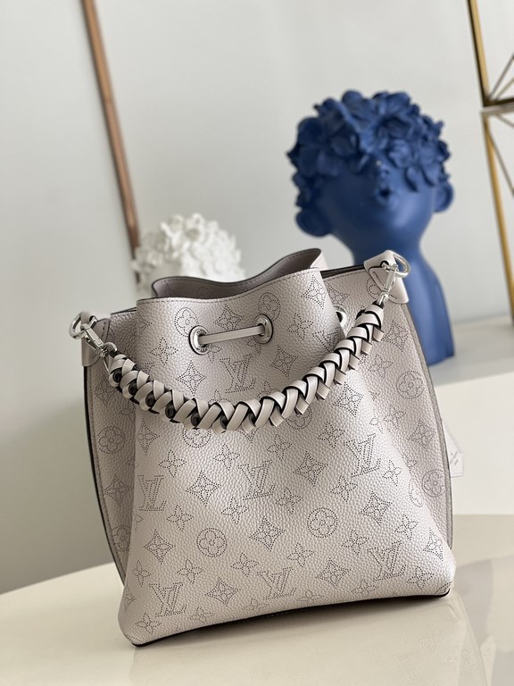 ExclusiveExclusive to M58788 in pearlized grey, this Muria bucket bag is crafted from cutout cowhide leather that lends a metallic sheen to the perforated Monogram pattern, and is finished with a leather name tag and key