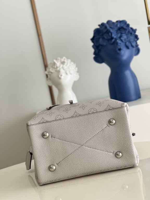 ExclusiveExclusive to M58788 in pearlized grey, this Muria bucket bag is crafted from cutout cowhide leather that lends a metallic sheen to the perforated Monogram pattern, and is finished with a leather name tag and key