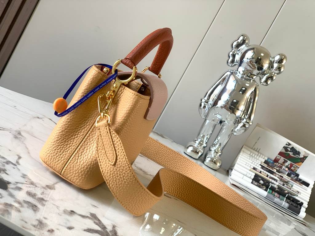 M59440 Apricot with Light Earth Gold Buckle]This Capucines mini bag is crafted from grained cowhide leather and features a color-blocked body and top handle and flap, LV lettering for visual interest, and a wide, removab