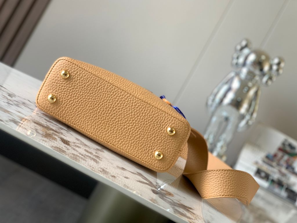 M59440 Apricot with Light Earth Gold Buckle]This Capucines mini bag is crafted from grained cowhide leather and features a color-blocked body and top handle and flap, LV lettering for visual interest, and a wide, removab