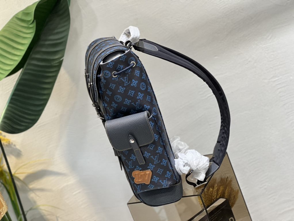 M46338 This Christopher MM backpack is made of coated canvas with a blue LV and Monogram floral pattern on a dark background. Finished with black leather trims and contrasting stitching, the bag is complemented by the LV