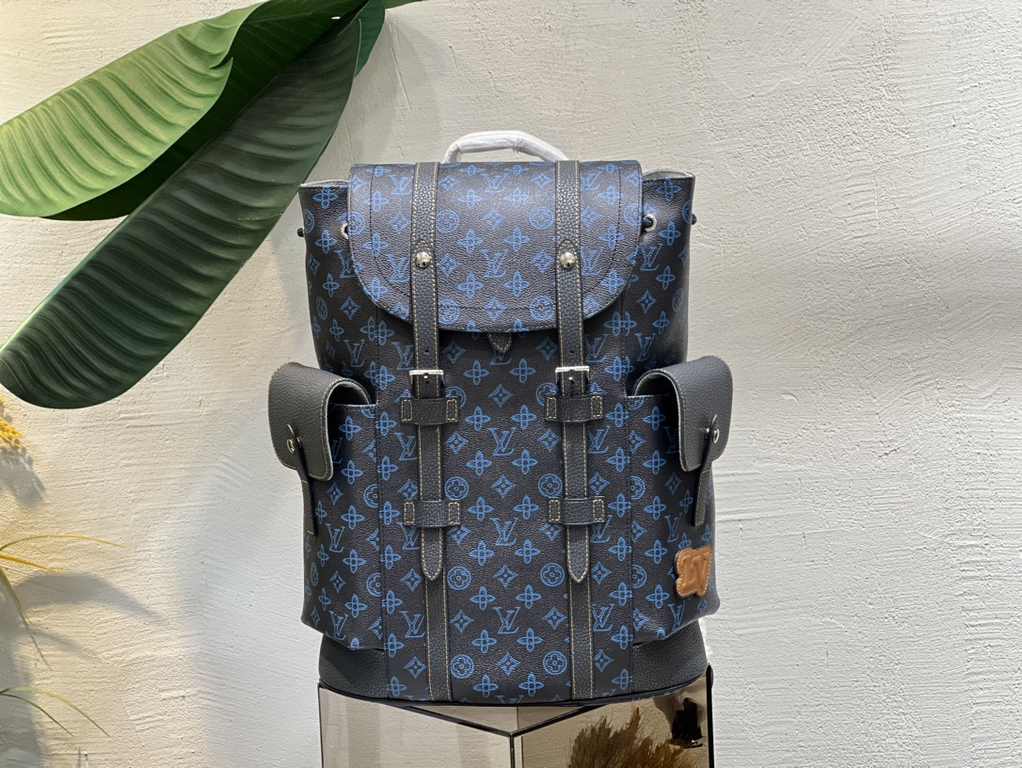 M46338 This Christopher MM backpack is made of coated canvas with a blue LV and Monogram floral pattern on a dark background. Finished with black leather trims and contrasting stitching, the bag is complemented by the LV