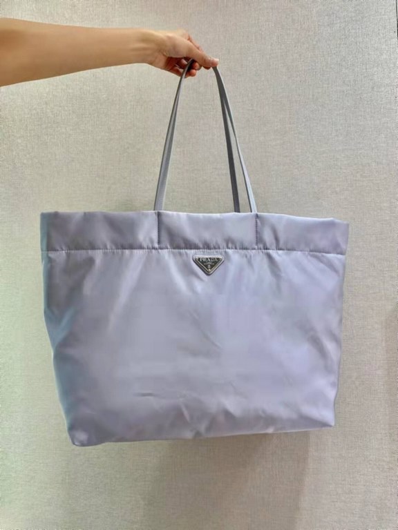 New Tote Bag 1BG107  This medium tote bag is crafted from innovative recycled nylon fabric for a minimalist and stylish design. Featuring a beautiful Saffiano leather carry handle, the bag is adorned with the iconic enam