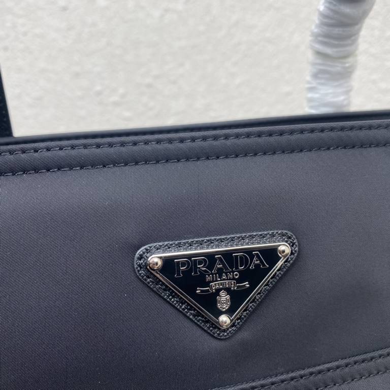 [Top Original]  New Tote Bag 1BG052  This traditional tote bag comes with a spacious front pocket and Saffiano leather carry handle. The distinctive triangular logo embellishment is a signature of the brand. Nylon was in