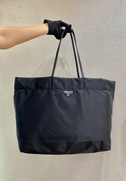 New Tote Bag 1BG107  This medium tote bag is crafted from innovative recycled nylon fabric for a minimalist and stylish design. Featuring a beautiful Saffiano leather carry handle, the bag is adorned with the iconic enam