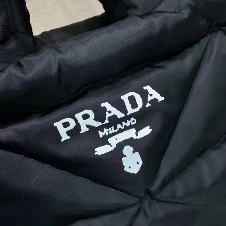 Prada's newest nylon tote bag, the 2VG082, features a lined and stitched triangle, a printed logo on the front, an enameled metal triangle logo on the side, and a cabinet with zippered and patch pockets. The iconic Prada