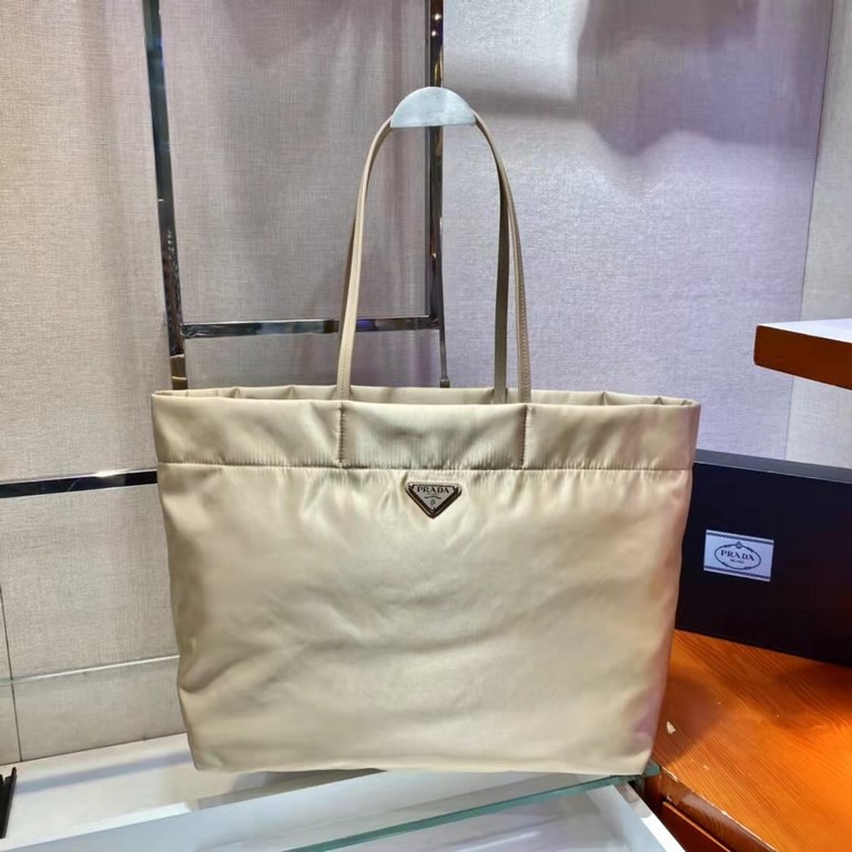 New Tote Bag 1BG107  This medium tote bag is crafted from innovative recycled nylon fabric for a minimalist and stylish design. Featuring a beautiful Saffiano leather carry handle, the bag is adorned with the iconic enam