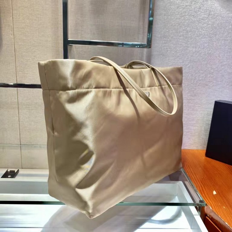 New Tote Bag 1BG107  This medium tote bag is crafted from innovative recycled nylon fabric for a minimalist and stylish design. Featuring a beautiful Saffiano leather carry handle, the bag is adorned with the iconic enam