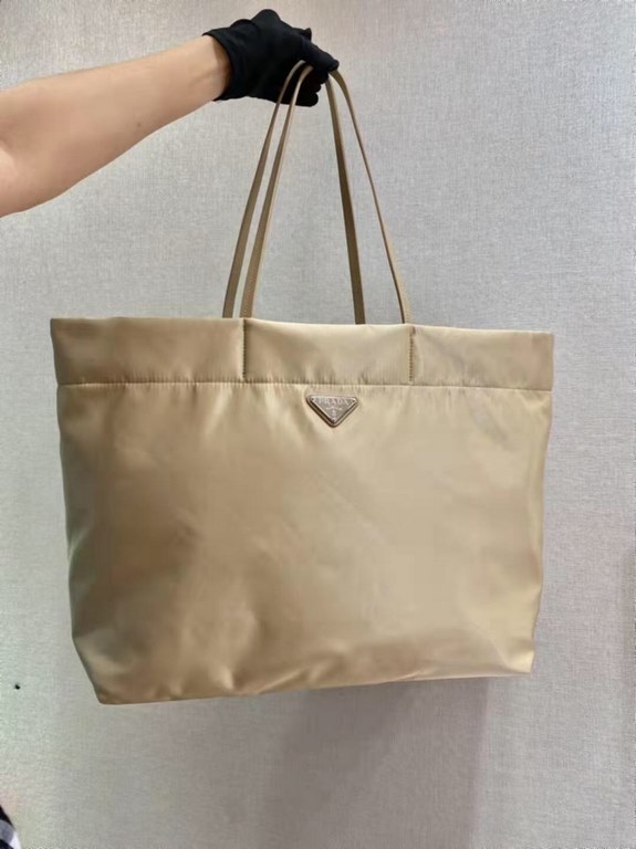 New Tote Bag 1BG107  This medium tote bag is crafted from innovative recycled nylon fabric for a minimalist and stylish design. Featuring a beautiful Saffiano leather carry handle, the bag is adorned with the iconic enam